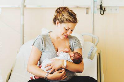 Glückliche Mutter, die ihr Neugeborenes im Krankenhaus im Arm hält.