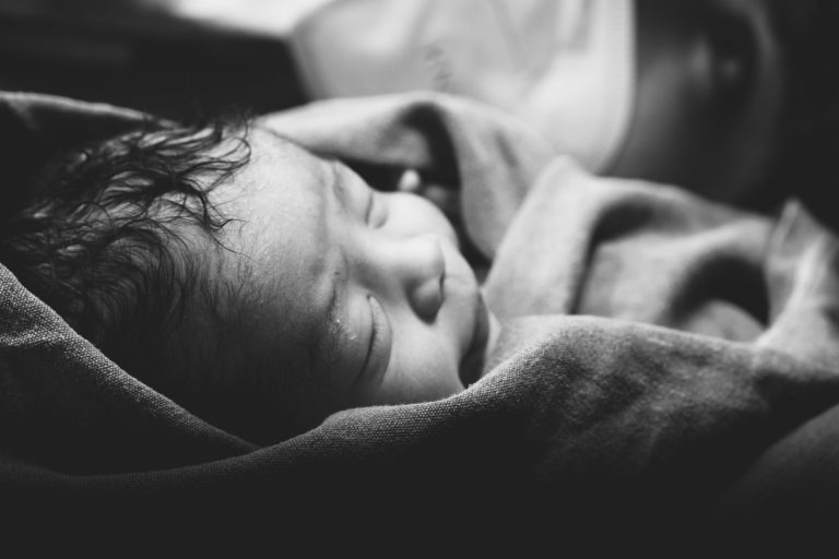 Ein Schwarz-Weiß Aufnahme eines Neugeborenen direkt nach der Hausgeburt
